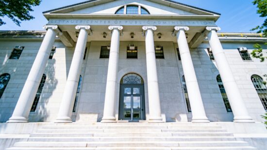 The beautiful center of public admissions building on Harvard's campus in Boston. Massive white stone columns in front of the white building, captured on a wide-angle lens.