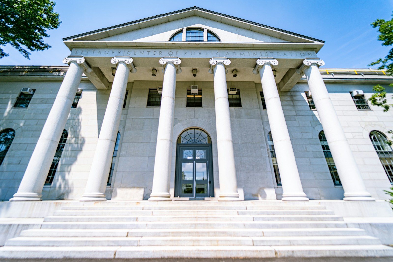 The beautiful center of public admissions building on Harvard's campus in Boston. Massive white stone columns in front of the white building, captured on a wide-angle lens.